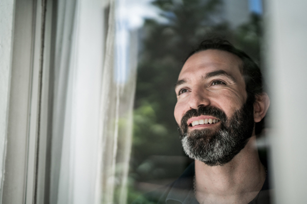 Man looking out window smiling
